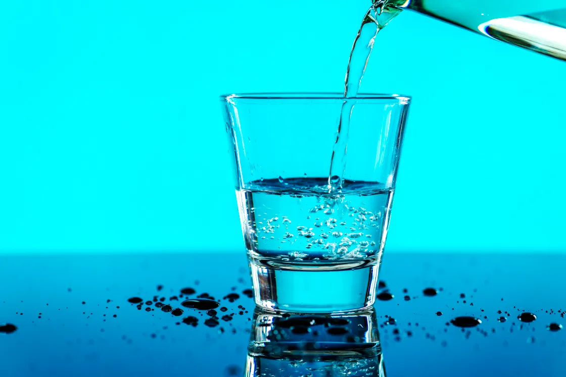 Bild von einem Glas mit Trinkwasser vor blauem Hintergrund