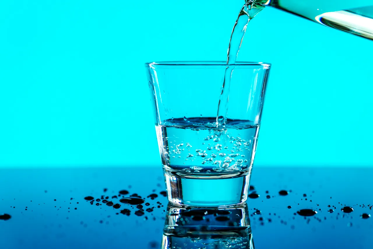 Bild von einem Glas mit Trinkwasser vor blauem Hintergrund